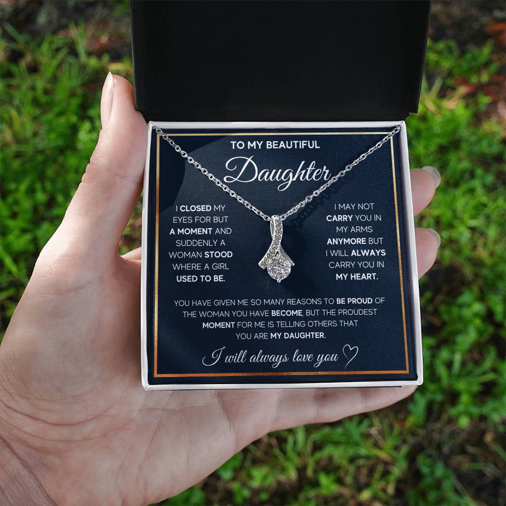 A woman holding a To My Daughter, I Will Always Carry You In My Heart - Alluring Beauty Necklace, a sentimental gift for her beloved daughter that says "I love you", from ShineOn Fulfillment.