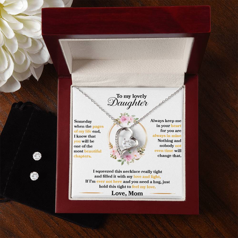 A Forever Love Necklace, named "To My Lovely Daughter, Hold This Tight To Feel My Love," from ShineOn Fulfillment rests in its jewelry box on a message card adorned with decorative flowers and heartfelt words from a mother to her daughter. Nearby, you can find a flower, a black velvet pouch, and an exquisite Cubic Zirconia Earring Set.