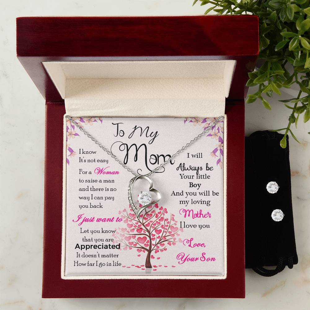 A ShineOn Fulfillment gift box includes a "To My Mom, I Know It's Not Easy" floral card with a heartfelt message and a Forever Love Necklace featuring a heart-shaped pendant in 14k white gold finish. Accompanying the box is a pair of stud earrings from the Cubic Zirconia Earring Set, elegantly placed in a black pouch.