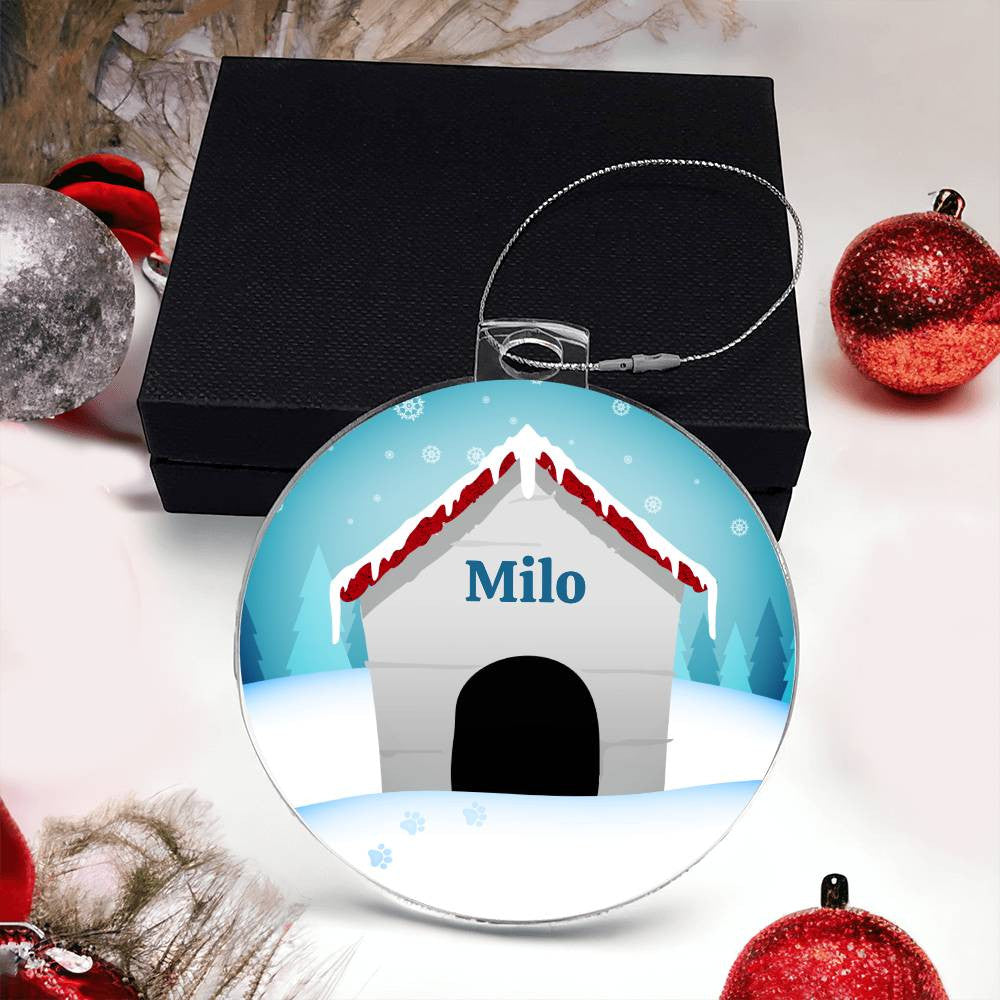 Introducing the "Honor Your Pup This Holiday with a Personalized Dog Name Christmas Ornament" by AnywherePOD. This distinctive keepsake is a round Christmas ornament made of premium acrylic, showcasing a doghouse adorned with a snow-covered roof and personalized with the name "Milo." Elegantly displayed in front of a black gift box, it is accompanied by red and silver baubles and snow-covered branches.