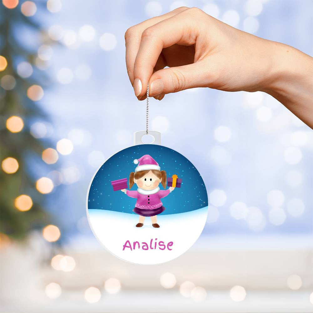 In a person's hand, they hold AnywherePOD's "Brighten Her Holiday with a Custom Girls' Name Christmas Ornament," showcasing a charming cartoon girl dressed in winter clothing and carrying gifts, set against a snowy scene. The ornament serves as a distinctive keepsake featuring the name "Analise," with a festive tree and twinkling lights adorning the background.