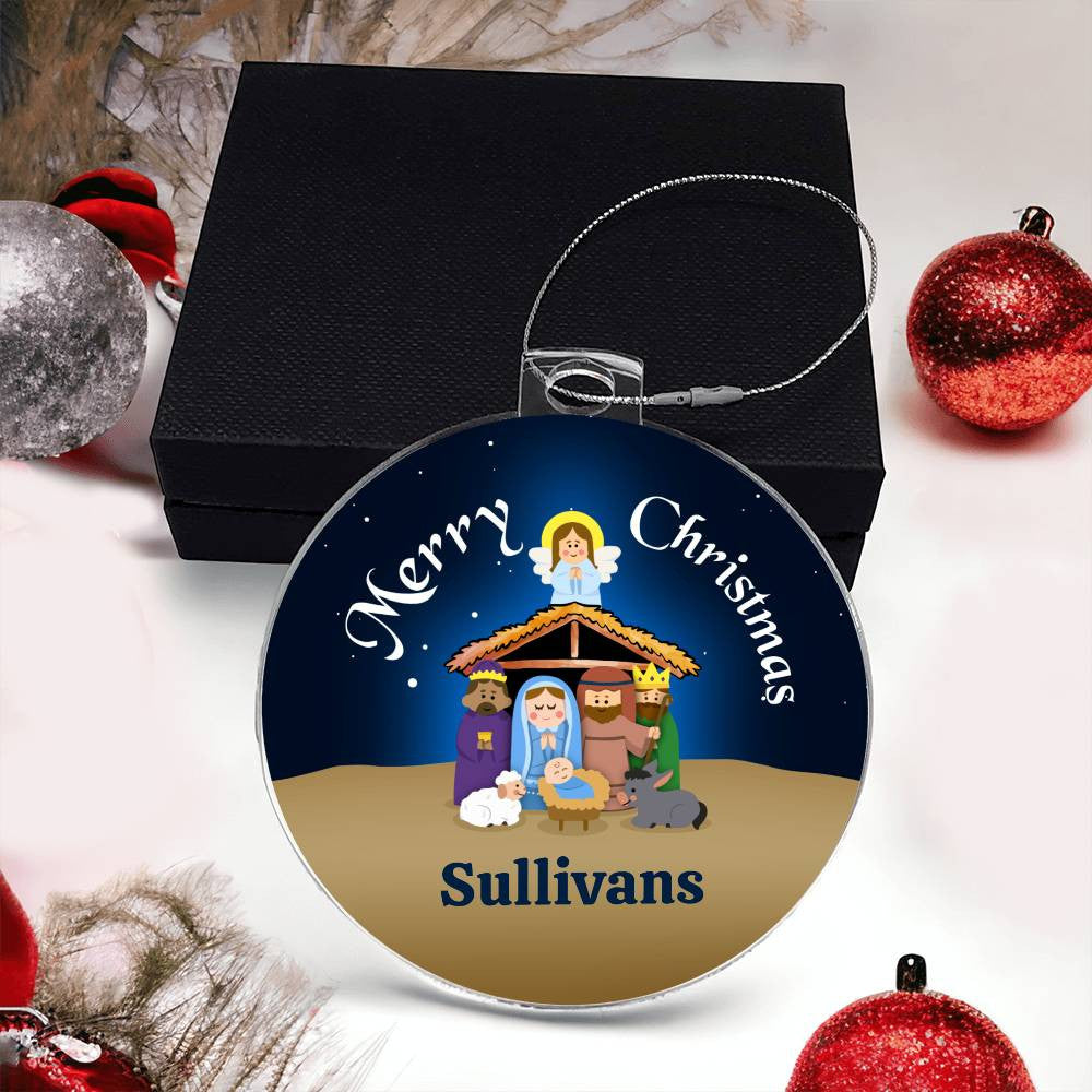 A round Christmas ornament from AnywherePOD, expertly crafted from premium acrylic, showcases a nativity scene with figures inside a stable and an angel above. The ornament bears the text "Merry Christmas" at the top and "Sullivans" at the bottom. This unique keepsake is presented in a black box surrounded by festive decorations.