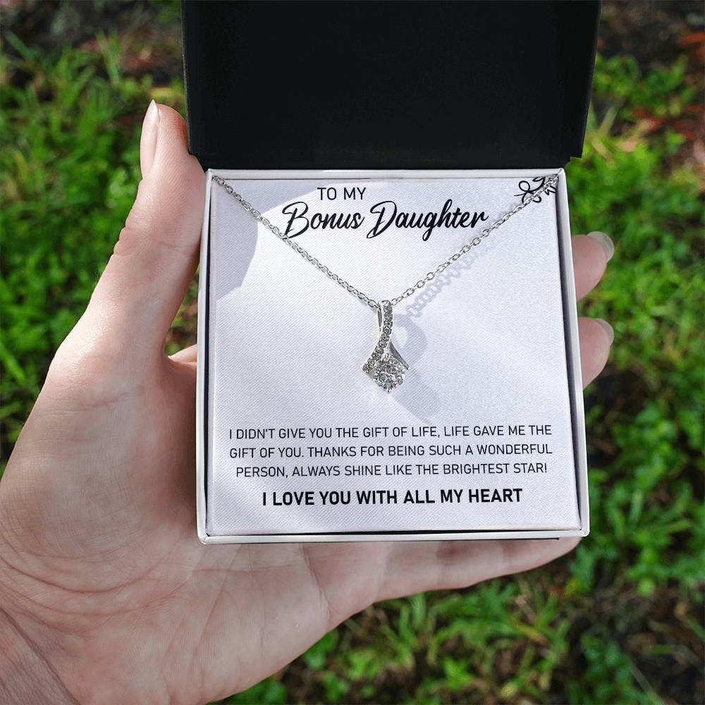 A woman holding the "To My Bonus Daughter, Always Shine Like The Brightest Star - Alluring Beauty Necklace" from ShineOn Fulfillment, a heartfelt gift that says "I love you" with all my heart.