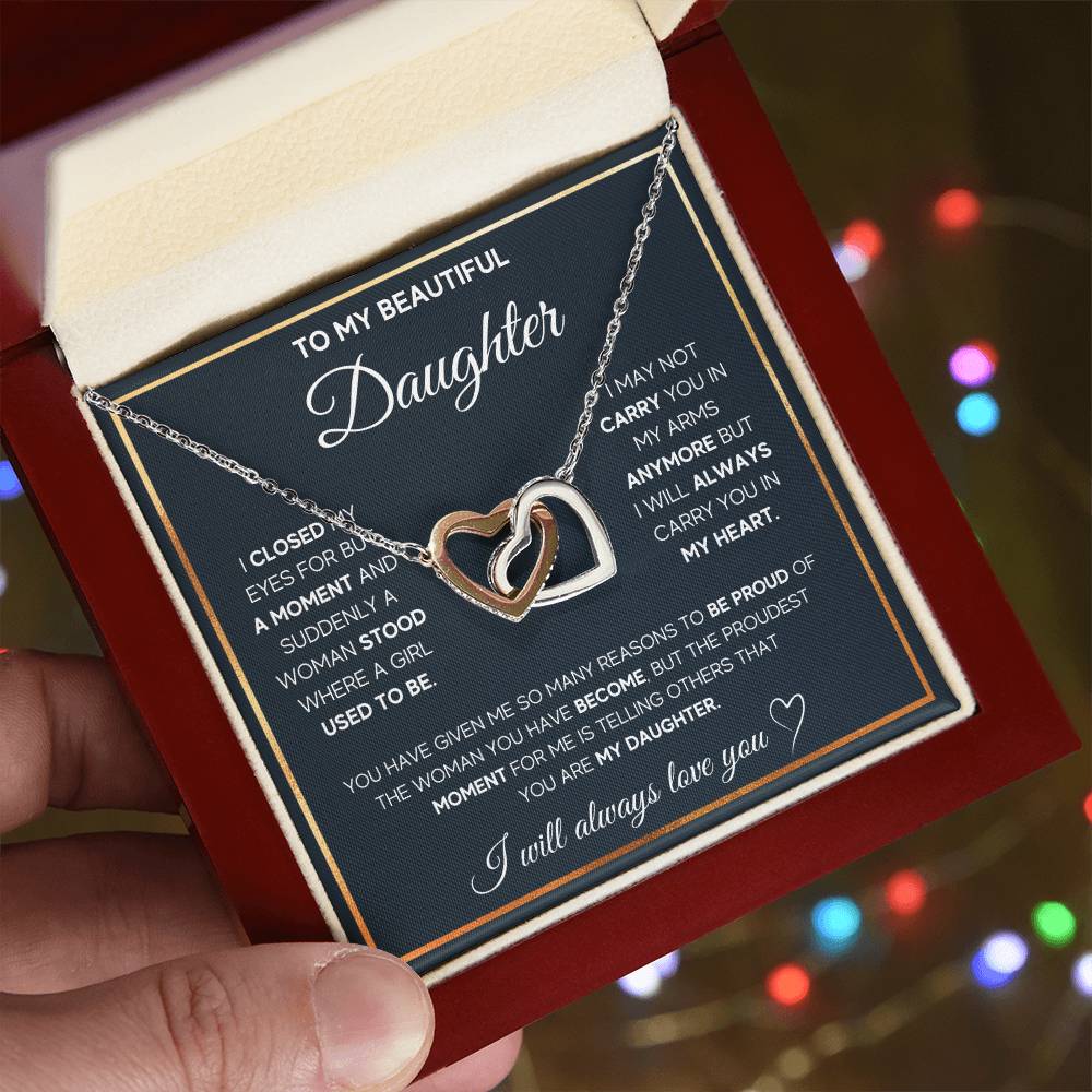 A person holding a gift box with a "To My Daughter, I Will Always Carry You In My Heart - Interlocking Hearts Necklace" by ShineOn Fulfillment in it, a perfect present for that special someone.