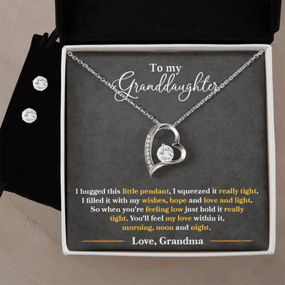 This jewelry gift box from ShineOn Fulfillment features the "To My Granddaughter, You'll Feel My Love Within This" – a Forever Love Necklace crafted with a 14k white gold finish, showcasing a heart-shaped pendant on a chain. It also includes a matching Cubic Zirconia Earring Set. The lid carries an endearing message from Grandma about love and support with the words: "To my Granddaughter.