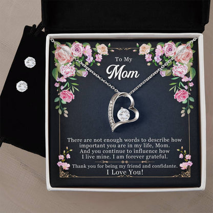 The To My Mom, Thank yOU For Being My Friend - Forever Love Necklace by ShineOn Fulfillment features a heart-shaped silver design with a diamond pendant, elegantly presented in a box. The lid is adorned with floral patterns and reads "To My Mom." Inside, you'll find a heartfelt message of gratitude. The soft, neutral background enhances its charm.