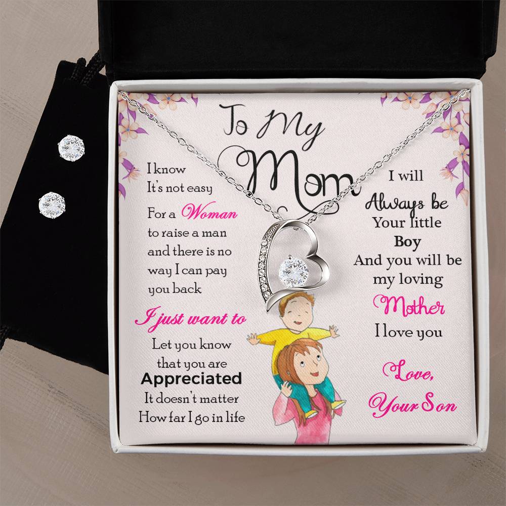 The ShineOn Fulfillment "To My Mom, I Will Always Be Your Little Boy - Forever Love Necklace" includes a heart-shaped pendant with a diamond set in a 14k white gold finish. This gift box also contains a heartfelt message from a son to his mother, expressing appreciation and love, complemented by artwork depicting a child embracing their mother.