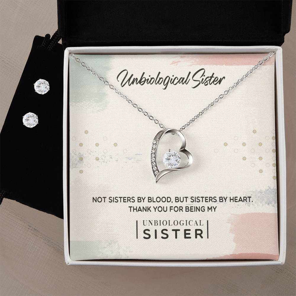 A silver, heart-shaped necklace from ShineOn Fulfillment's "To My Unbiological Sister, Thank You - Forever Love Necklace" collection features a small gemstone and comes beautifully presented in a black jewelry box with the inscription "Not sisters by blood, but sisters by heart. Thank you for being my unbiological sister." Paired with this necklace is an exquisite set of sparkling Cubic Zirconia Earrings set in a 14k white gold finish.