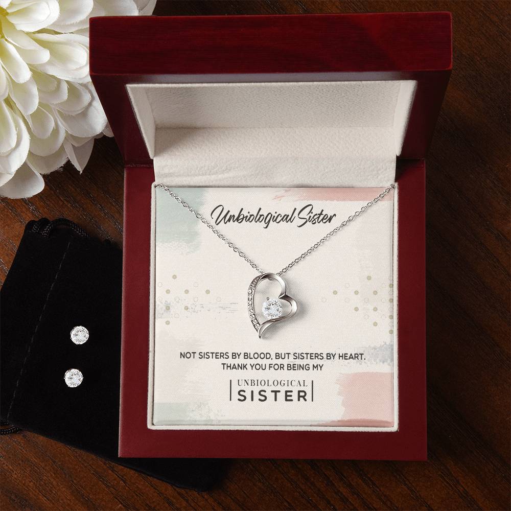 The "To My Unbiological Sister, Thank You - Forever Love Necklace" from ShineOn Fulfillment features a silver heart-shaped pendant with a gemstone, elegantly presented in a red jewelry box. Inside the box, the words "Unbiological Sister" are displayed alongside a touching message: "Not sisters by blood, but sisters by heart. Thank you for being my unbiological sister." A white flower rests nearby.