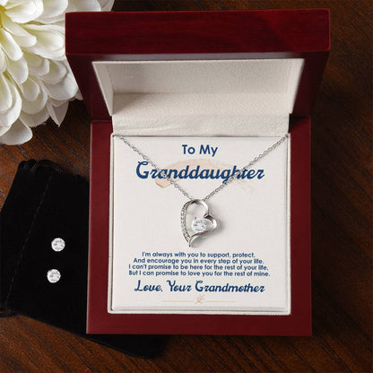 A silver heart-shaped Forever Love Necklace, featuring a 14k white gold finish and designed by ShineOn Fulfillment, is beautifully presented in an open jewelry box. Inside, the message reads, "To My Granddaughter...Love, Your Grandmother." A white flower in the background adds an elegant touch to this special piece titled "To My Granddaughter, I Love You For The Rest Of My Life.