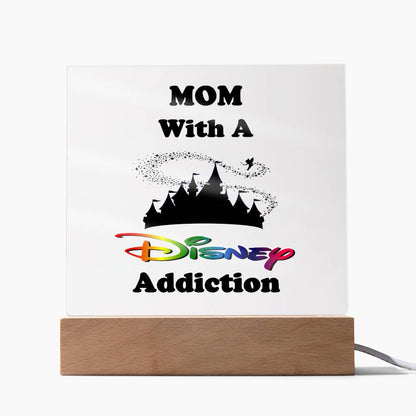 The "Disney-Obsessed Mom: Where Magic Meets Motherhood!" light box by ShineOn Fulfillment is a square acrylic plaque featuring the phrase "MOM With A Disney Addiction" and a silhouette of the iconic Magic Kingdom castle. The word "Disney" stands out with its vibrant multicolored style, making it an ideal decorative piece for any mom who loves Disney.