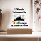 An enchanting plaque from ShineOn Fulfillment, titled "Disney Obsessed: Where Magic Meets Everyday Life!," features the phrase "I Work To Support My Disney Addiction" with "Disney" highlighted in vibrant colors. The plaque is made of acrylic and set on a wooden base, showcasing a silhouette of a castle with Pixie dust from Tinker Bell in the background—ideal for any Disney enthusiast's collection. It stands proudly on a white tabletop against a neutral wall.