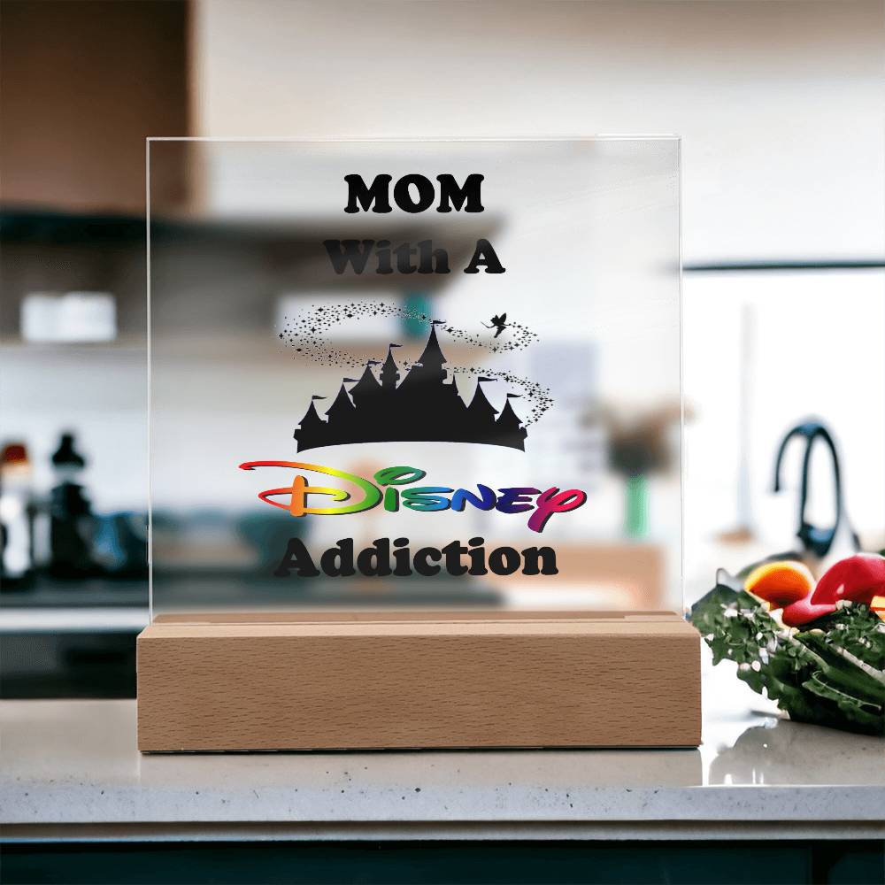 On the kitchen countertop sits an acrylic plaque named "Disney-Obsessed Mom: Where Magic Meets Motherhood!" by ShineOn Fulfillment, displaying a silhouette of a castle and Tinkerbell. It's a charming gift option, with fresh vegetables in the background enhancing the scene's appeal.