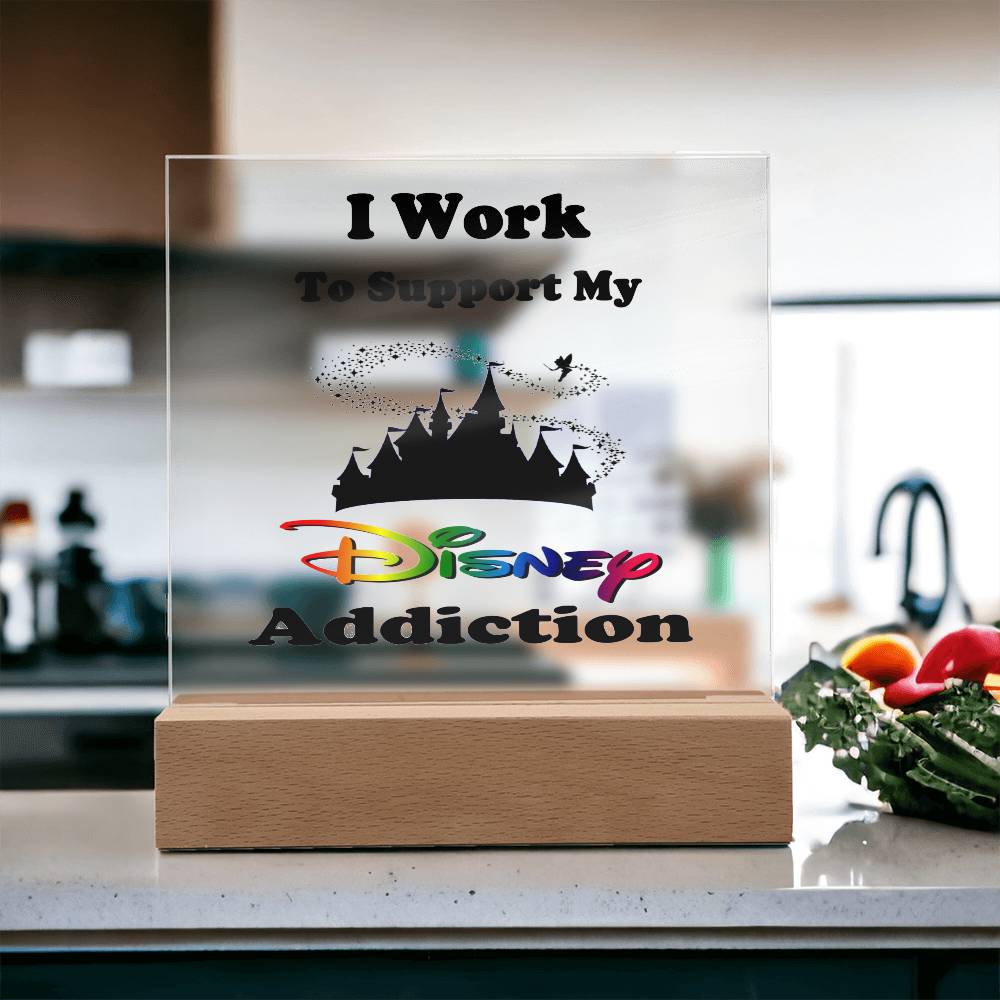 A decorative printed square acrylic plaque from ShineOn Fulfillment, titled "Disney Obsessed: Where Magic Meets Everyday Life!", sits on the kitchen counter. It features a castle silhouette and a vibrant Disney logo along with the phrase "I Work to Support My Disney Addiction." This bright space, complete with fresh produce nearby, is perfect for any Disney fan.